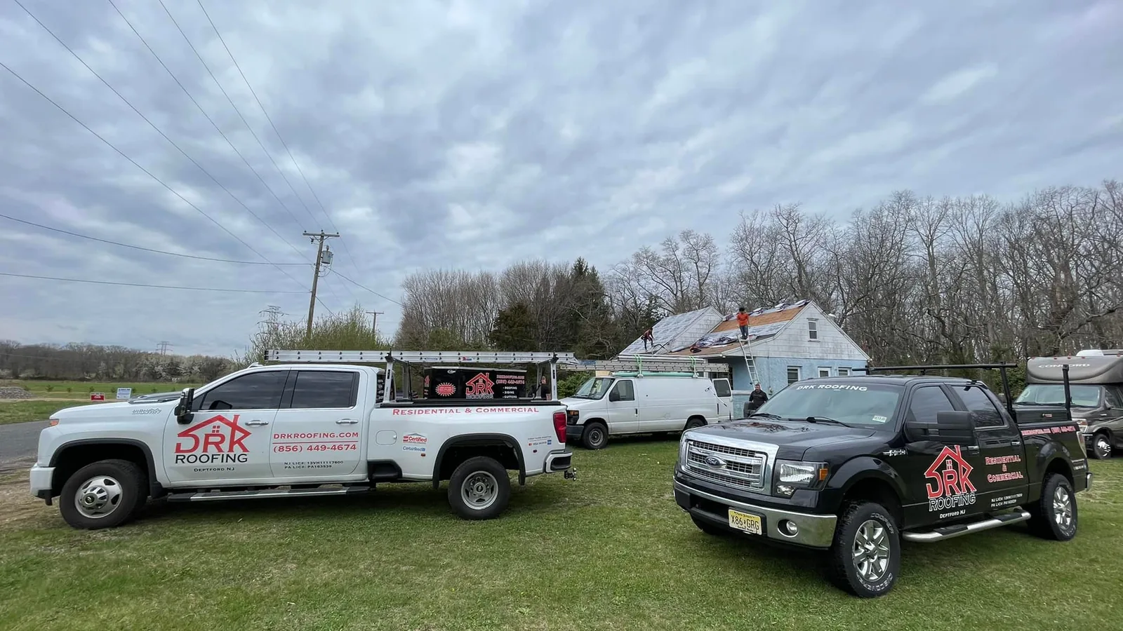 Roofing company pickup trucks parked on the lawn at a home job site