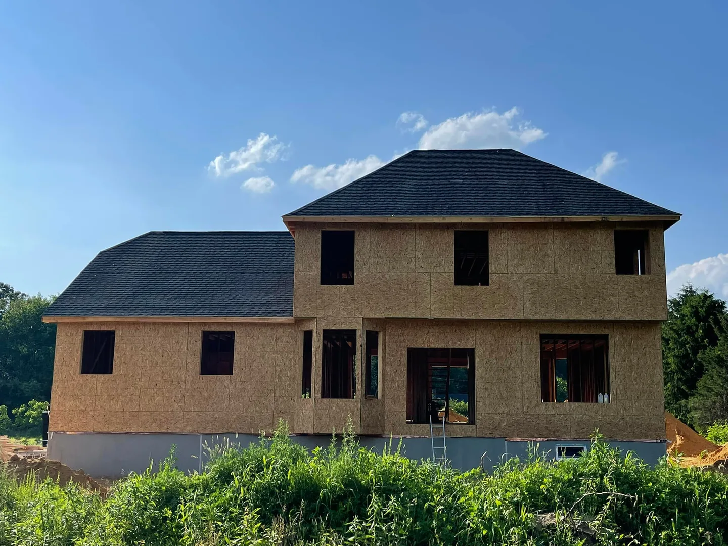 New construction house with sheathed walls and a new shingle roof, commercial roofing