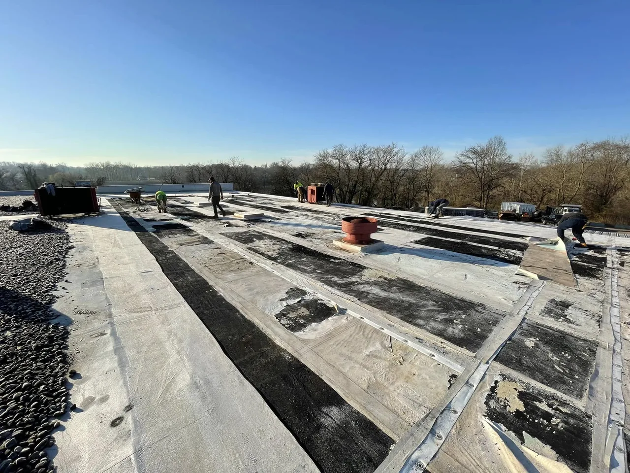 Crew working on a large flat roof during a commercial roofing TPO installation
