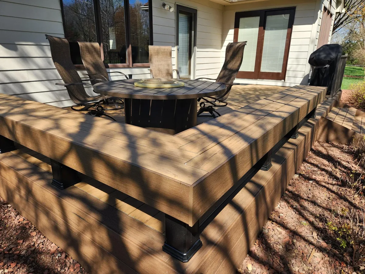 Brown composite deck with a built in bench, black post sleeves and side steps, deck builder