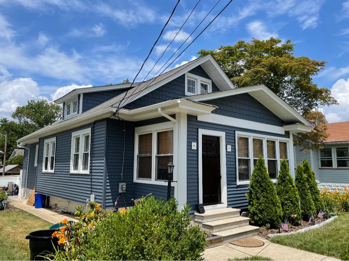 Front door with white trim on a blue sided bungalow, exterior doors