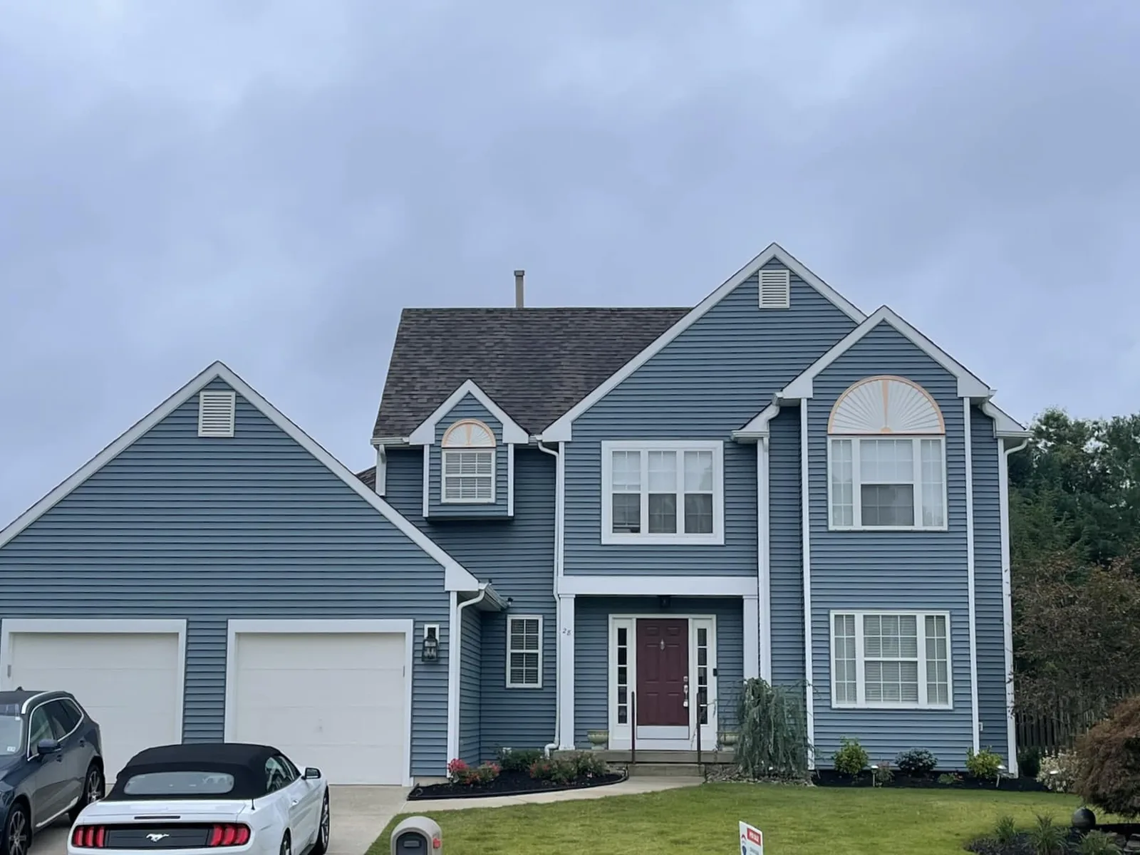 Blue vinyl sided colonial with a new entry door and white trim, exterior doors