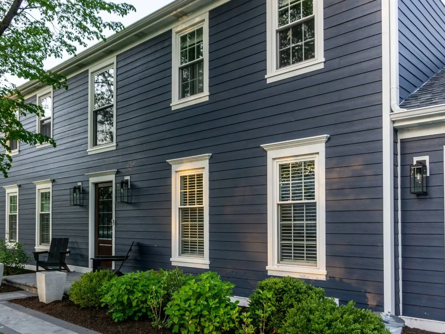 Deep blue lap fiber cement siding with white window trim on a two story colonial