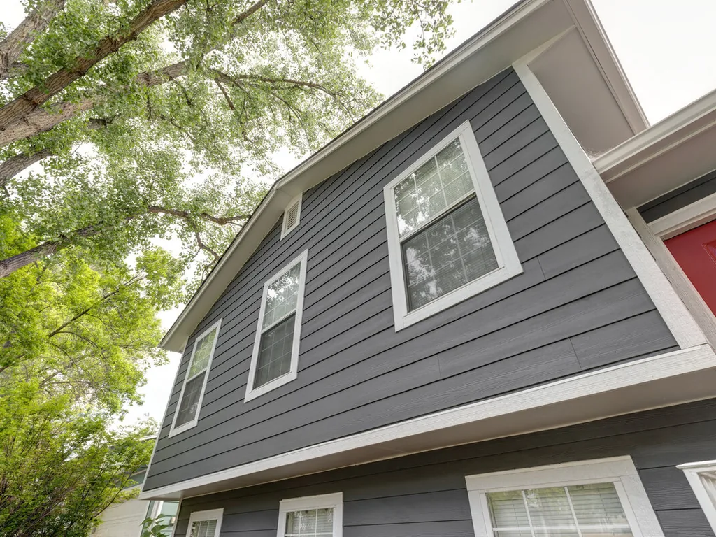 Dark gray lap fiber cement siding with white window and corner trim on a two story home