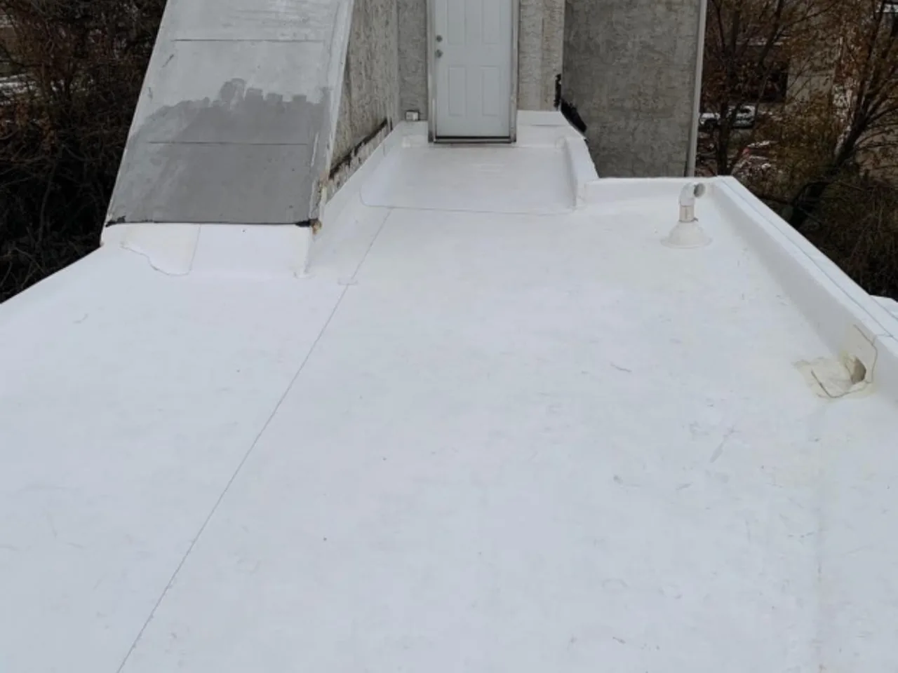New white flat roofing membrane leading to an exterior door