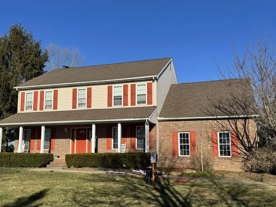 Colonial home with red shutters under a new Barkwood asphalt shingle roof, roof replacement