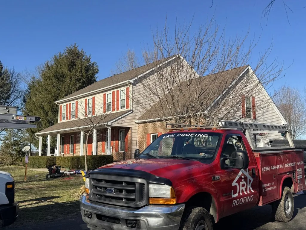 Red company pickup and a ladder at a colonial during a roof replacement