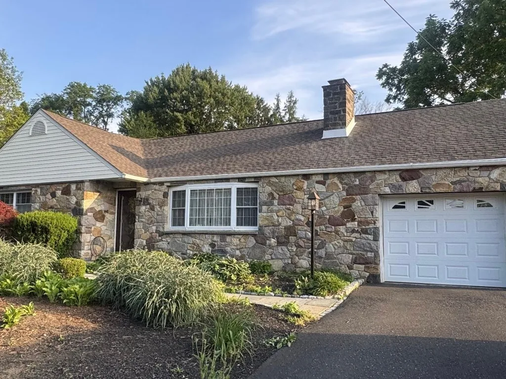 Stone ranch home with a new Barkwood asphalt shingle roof and a white garage door, roof replacement