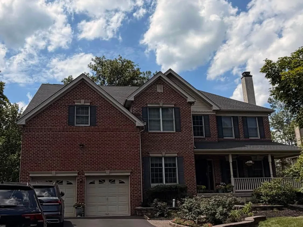 Brick colonial with a new charcoal asphalt shingle roof and a covered porch, roof replacement