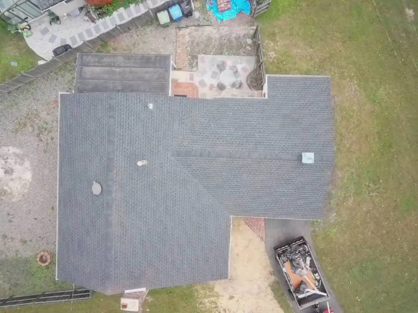 New charcoal asphalt shingle roof on a ranch home seen straight down from above, roof replacement