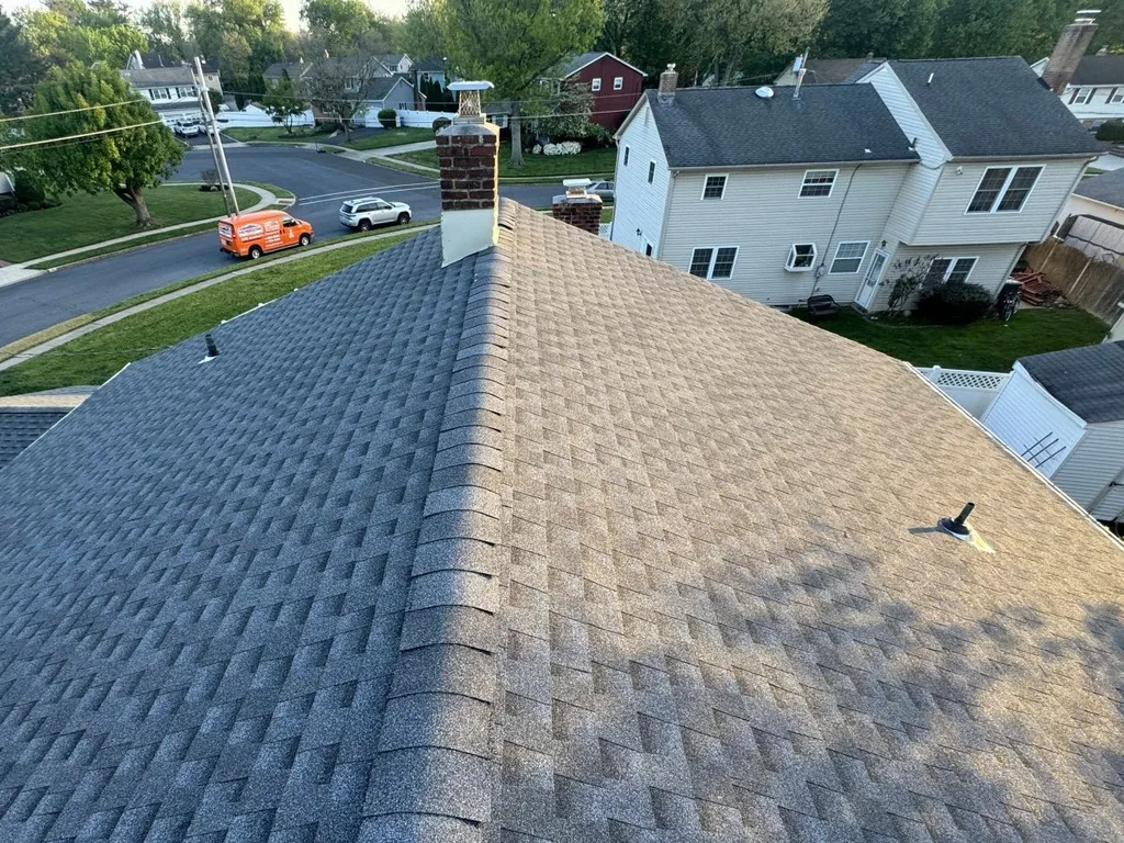 New asphalt shingle roof ridge and a brick chimney with new flashing, roof replacement