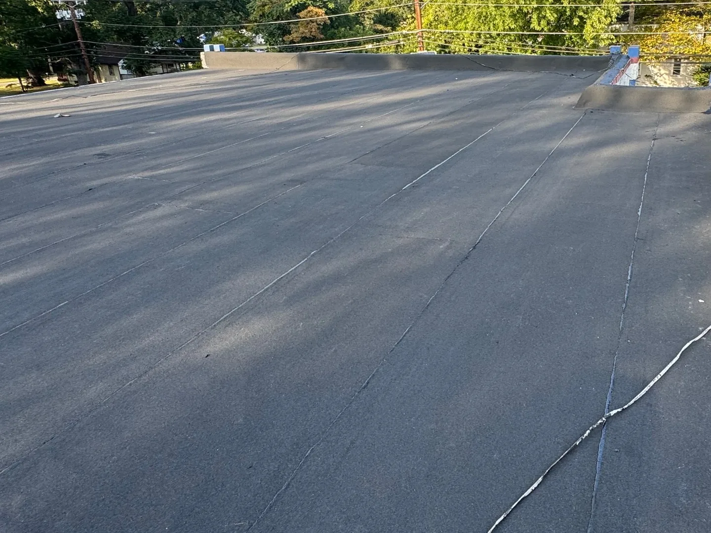 Finished black flat roofing membrane with sealed seams and a raised curb, flat roofing