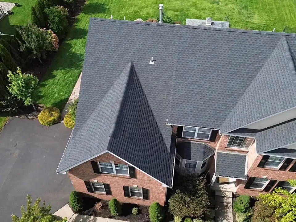 New dark gray asphalt shingle roof on a brick colonial seen from above, roof replacement
