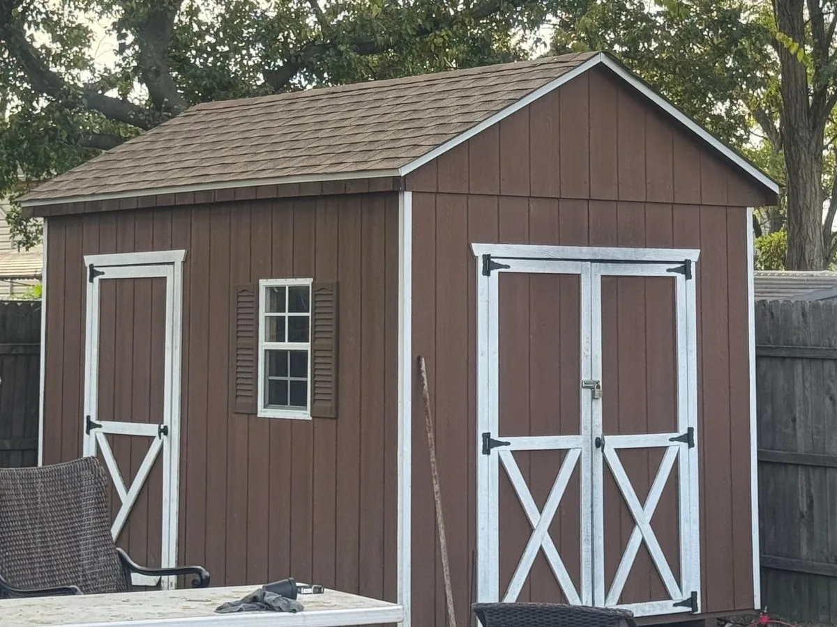 Backyard shed with a new brown asphalt shingle roof, roof replacement