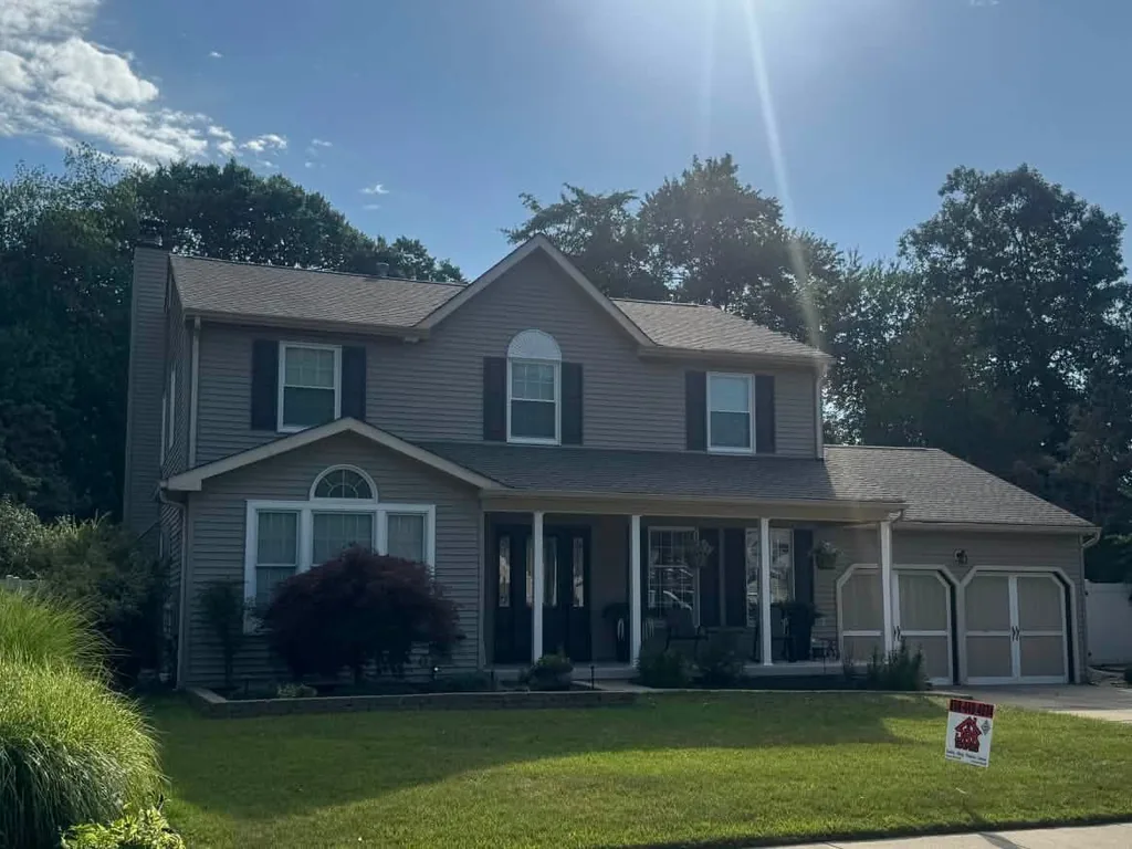 Colonial home with a new Weathered Wood asphalt shingle roof and a company yard sign, roof replacement