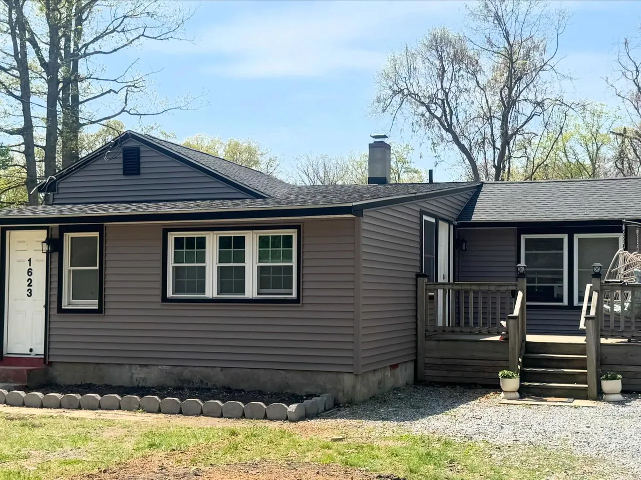 Taupe vinyl siding with black window trim on a ranch home with a wood deck, vinyl siding