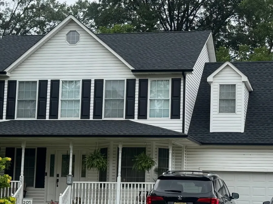New black gutters under a black shingle roof on a white home, gutter installation