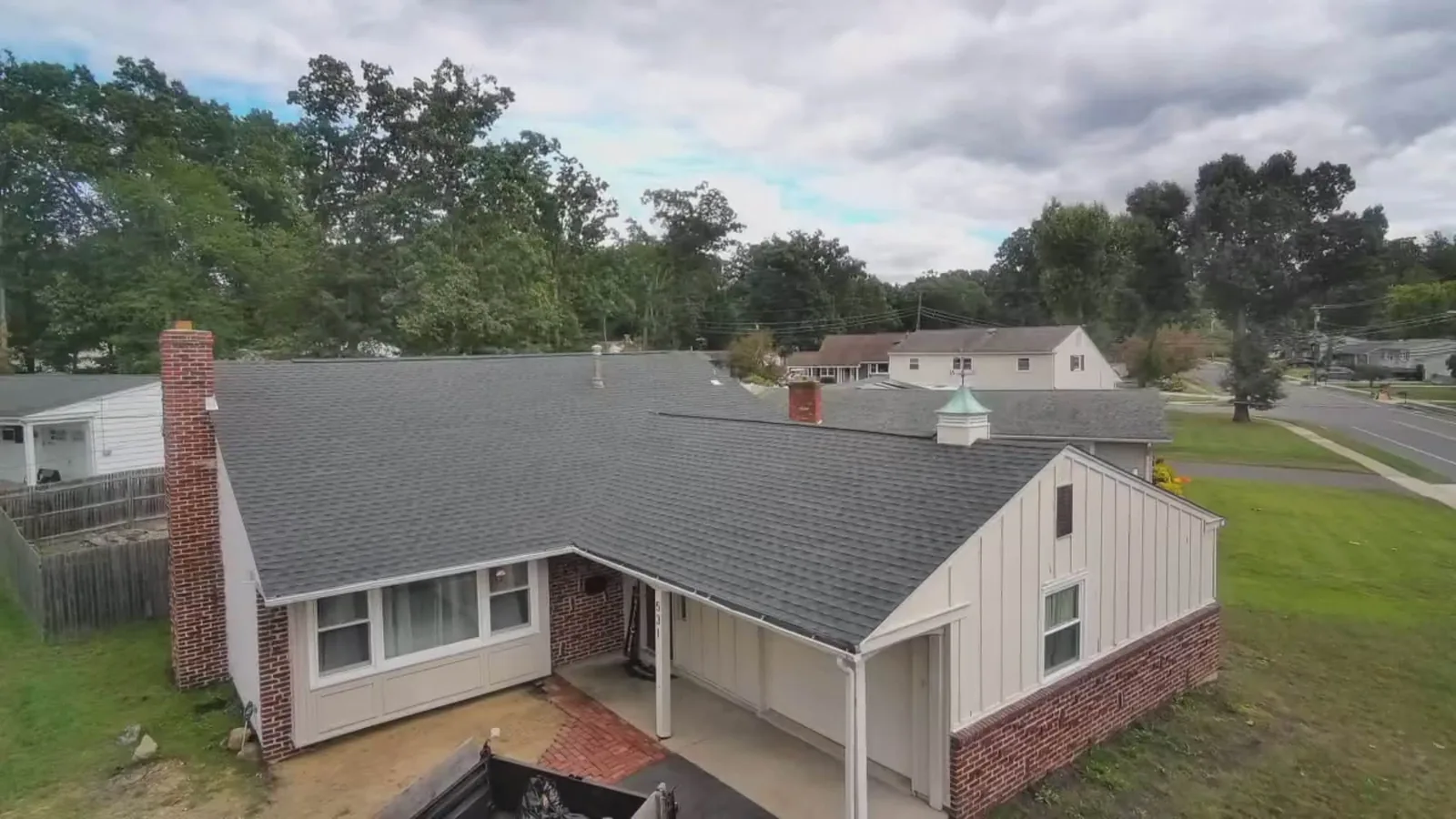 Aerial view of a new charcoal asphalt shingle roof on a ranch home, roofing contractor