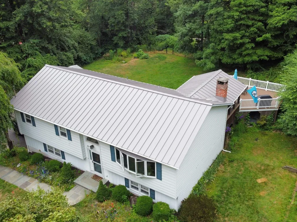 Aerial view of a light gray standing seam metal roof on a raised ranch house, metal roofing