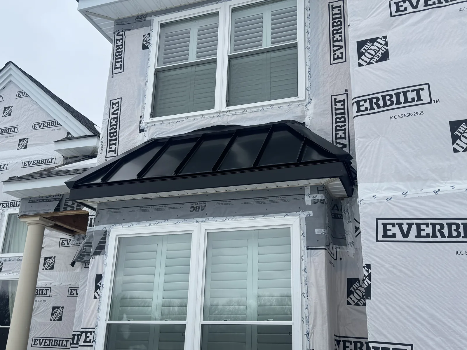 Black standing seam metal roofing on a bay window roof with house wrap around it