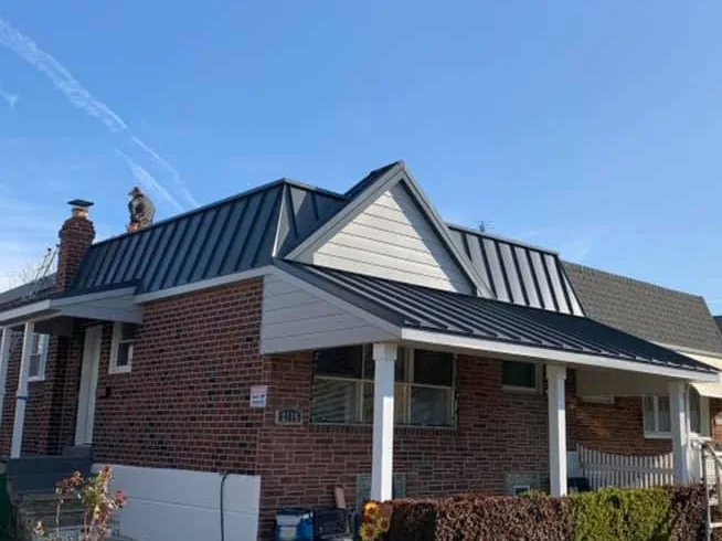 Dark standing seam metal roofing over the porch of a brick home