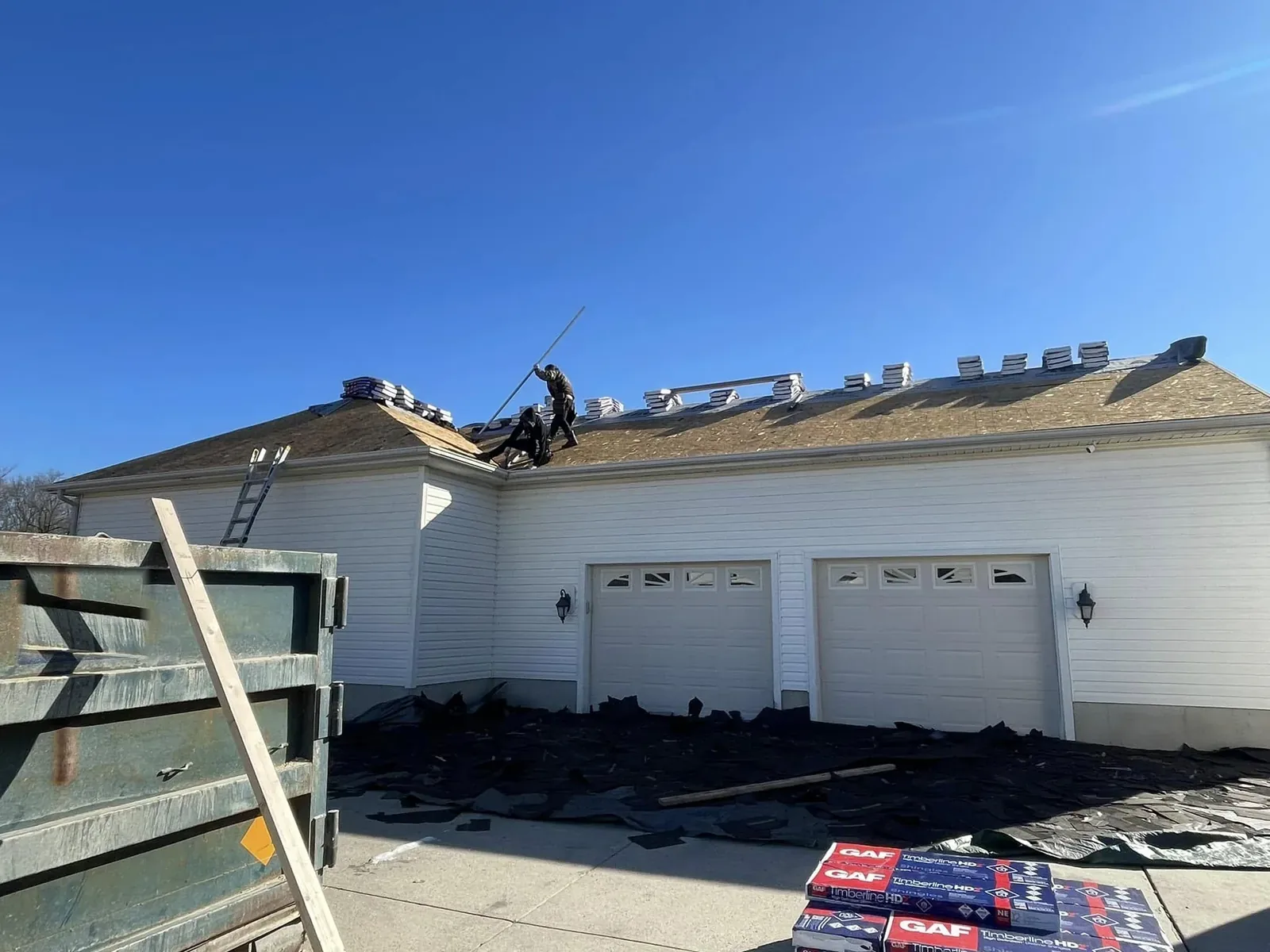 Crew tearing off an old shingle roof on a ranch home during a roof replacement