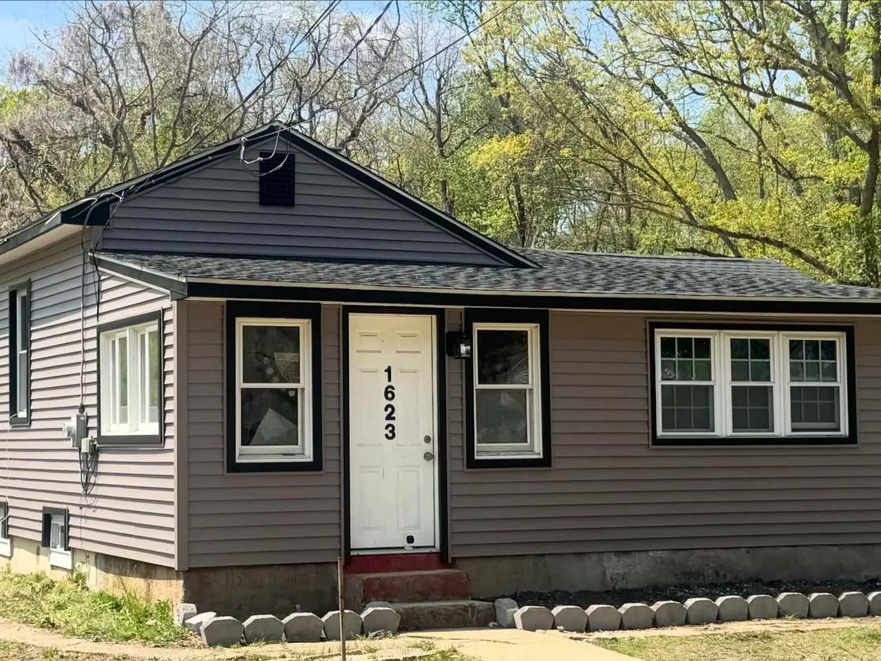 Brown vinyl siding with white trim on a small ranch home
