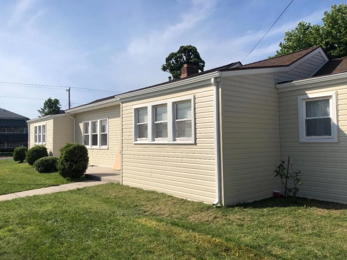 Cream vinyl siding along the side of a ranch home with white windows